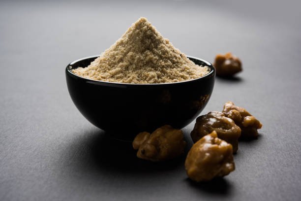Asafoetida cake and powder or Hing or Heeng which is an important ingredient in Indian food recipes with big wooden spoon and mortar, selective focus
