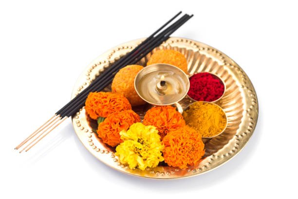 Beautifully Decorated Pooja Thali for festival celebration to worship, haldi or turmeric powder and kumkum, flowers, scented sticks in brass plate, hindu puja thali